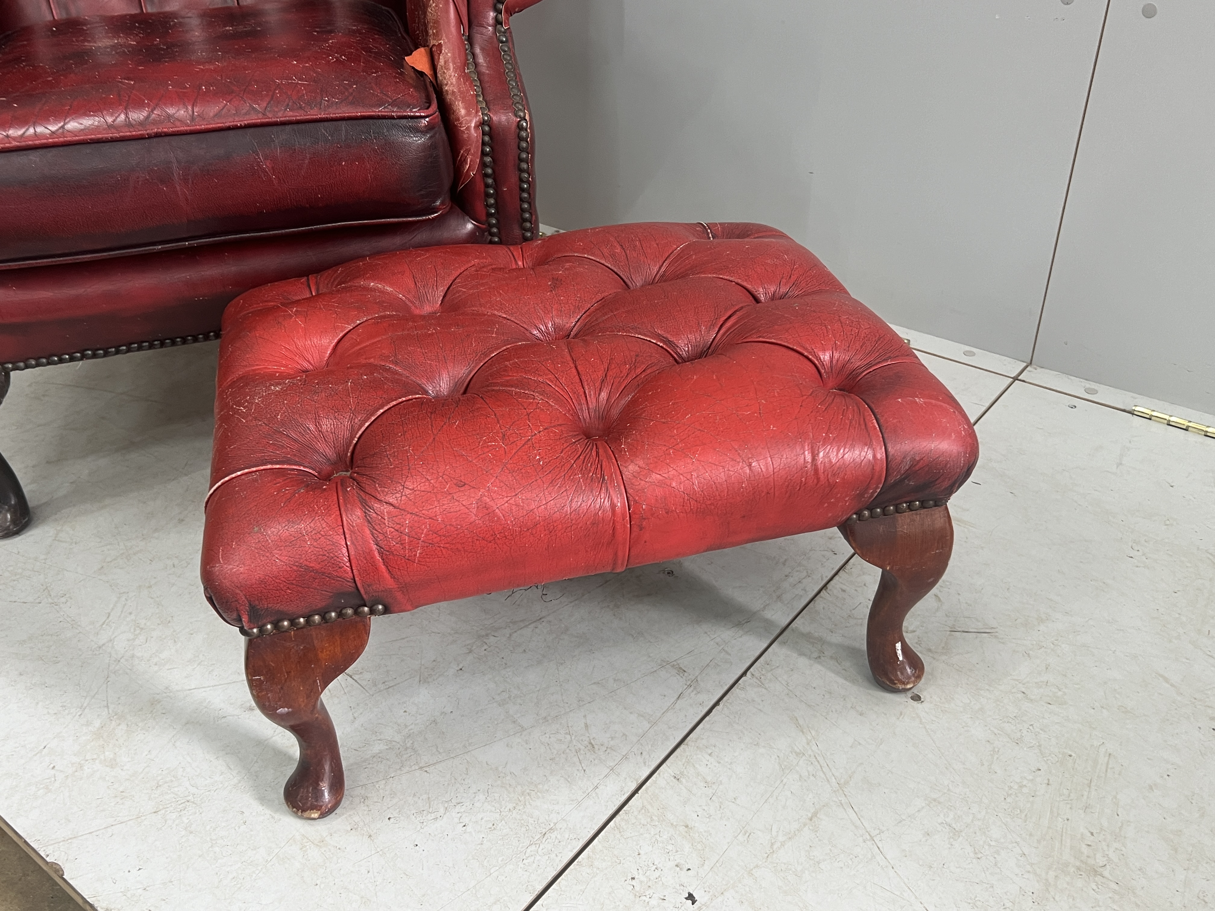 A Victorian style leather armchair, width 82cm, depth 80cm, height 110cm and footstool